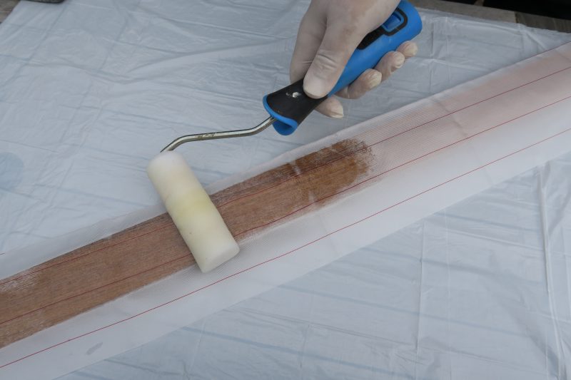 Rolling more epoxy over peel ply over wet epoxy resin