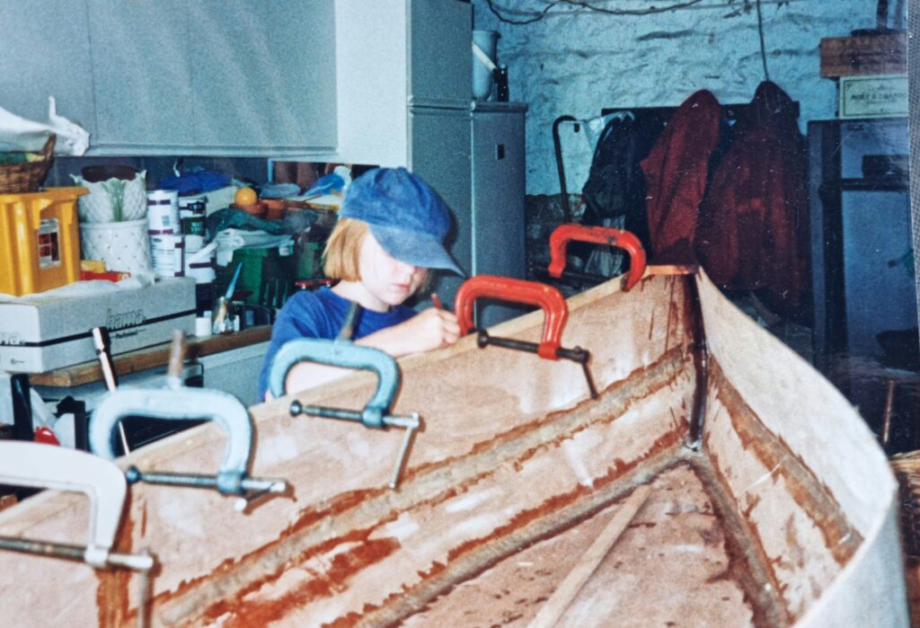 Polly Robinson as a child next to her grandads wooden boat 
