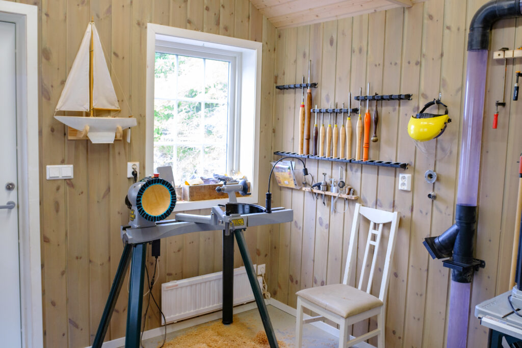 The inside of a workshop, with various tools hung up on the wall and a workstation set up.