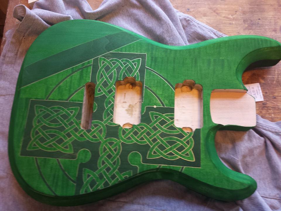 A green wooden guitar with a Celtic pattern on it